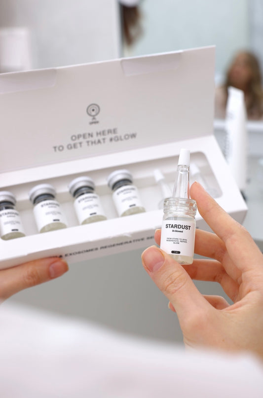 STARDUST Illuminating Serum Skincare Bundle Set Collection Set with 4 ampoules, showcasing a hand holding one ampoule.